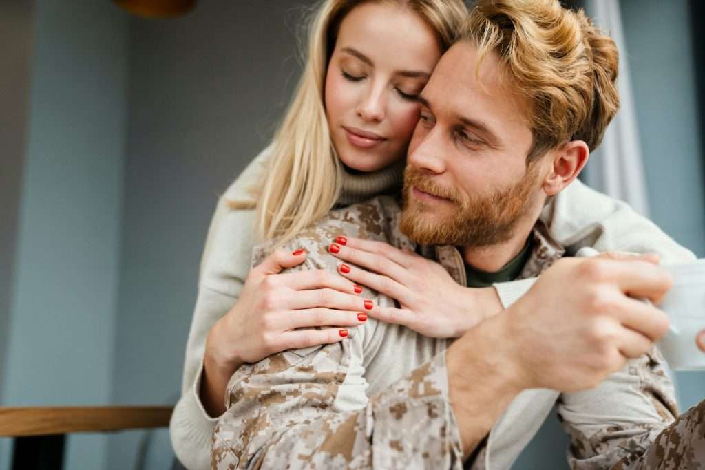 Beautiful young happy couple drinking coffee and hugging indoors